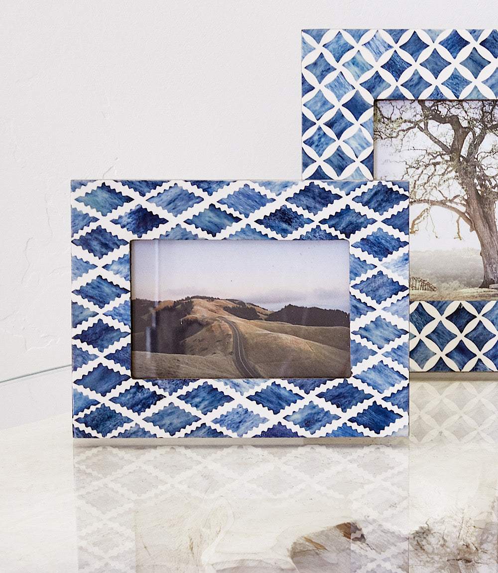 Handcrafted mosaic bone picture frame in blue and white geometric pattern holding 4x6 photo, standing on glass surface