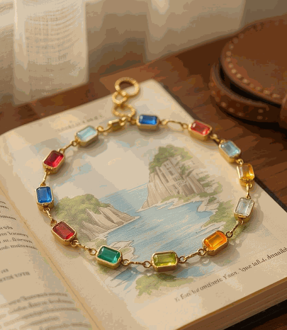 Colorful gemstone bracelet with 18K gold filled setting and rectangular multicolored stones on a stretch band placed on an open book.