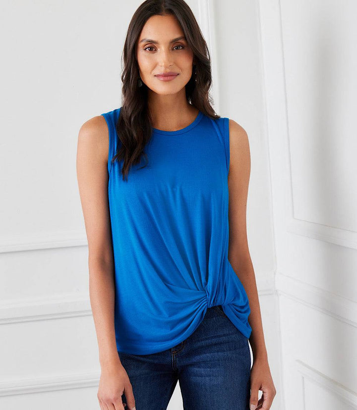 Woman wearing a blue sleeveless pick-up top with a twisted hem detail and crew neck.