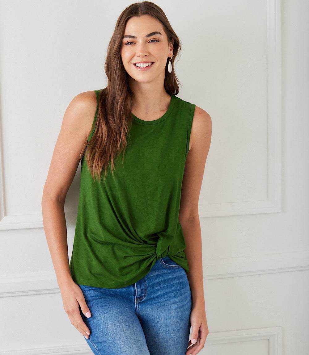 Woman wearing green sleeveless pick-up top with twist hem and crew neck, paired with blue jeans