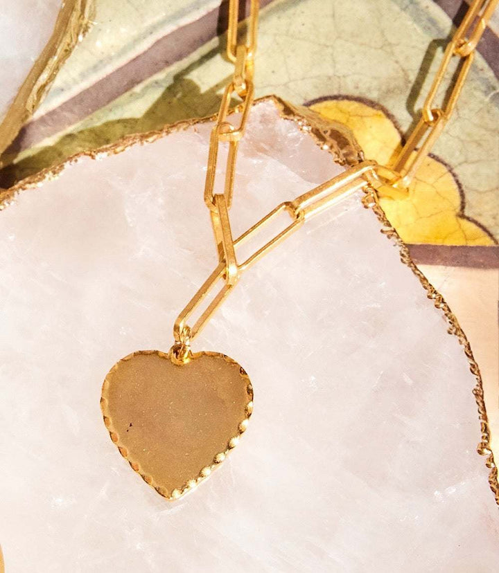 Gold Heart Disc Necklace with chain-link design on crystal background