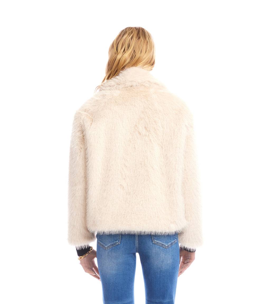 Back view of cropped beige faux fur jacket with drop shoulder sleeves worn with blue jeans