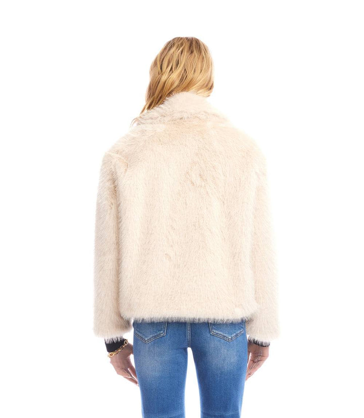 Back view of cropped beige faux fur jacket with drop shoulder sleeves worn with blue jeans