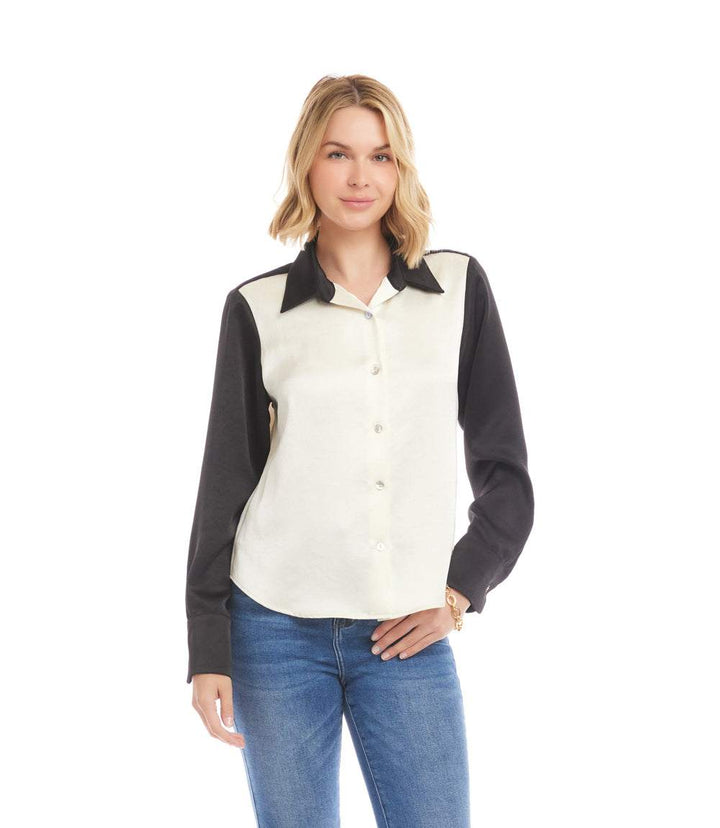 Woman wearing a long sleeve satin colorblock shirt with contrast black sleeves and collar, button-down front, and relaxed fit paired with blue jeans.