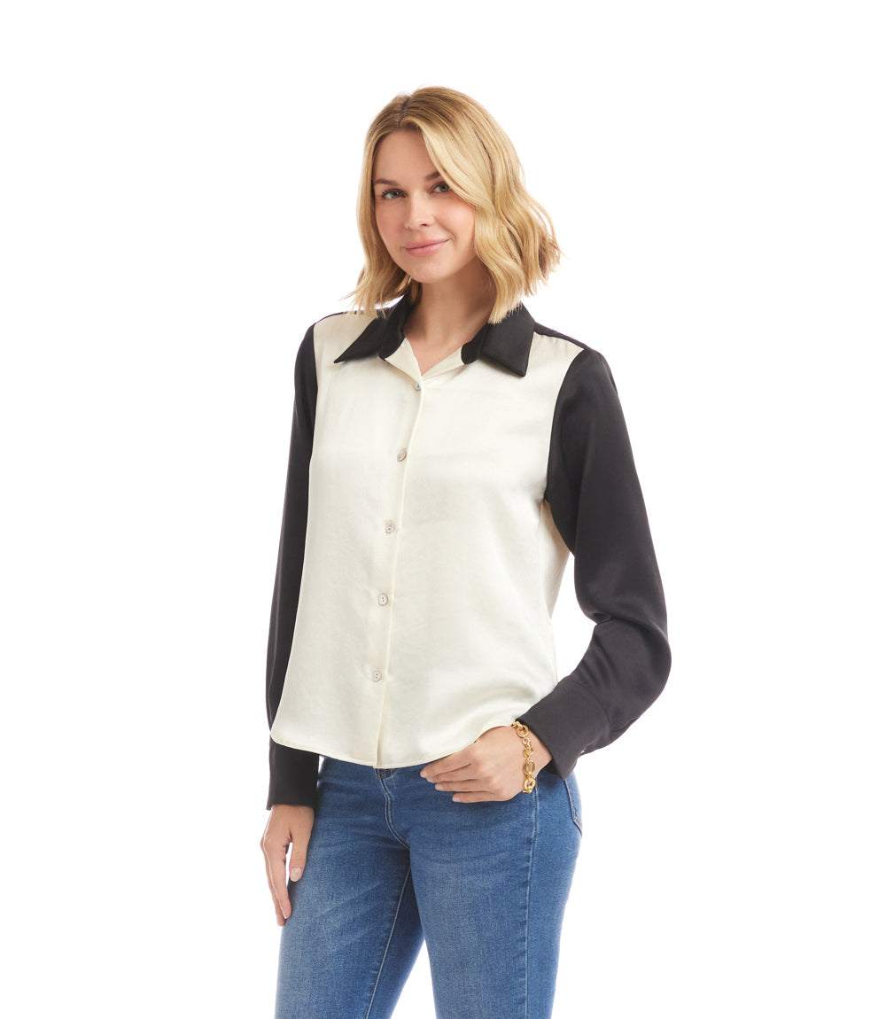 Woman wearing a long sleeve satin colorblock shirt with black sleeves and collar and white front, paired with blue jeans.
