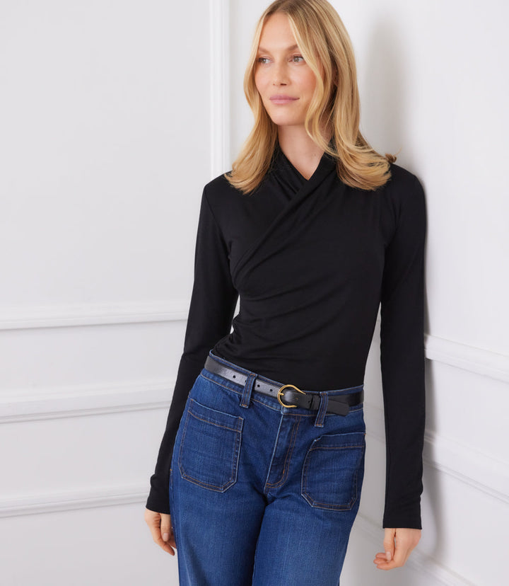 Woman wearing black long sleeve crossover top with side shirring and blue jeans