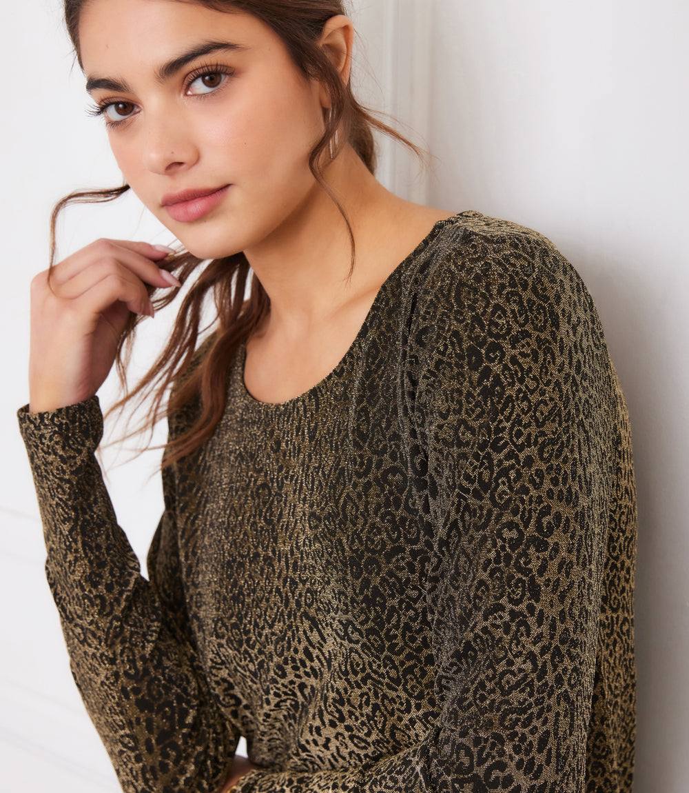 woman wearing long sleeve metallic knit leopard print top with scoop neck and shirttail hem