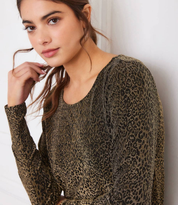 woman wearing long sleeve metallic knit leopard print top with scoop neck and shirttail hem