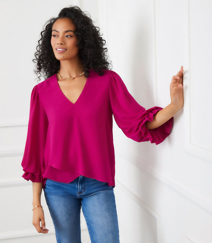 Woman wearing magenta layered sleeve asymmetric top with V-neck and bishop sleeves