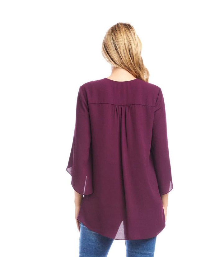 Back view of petite size bracelet sleeve asymmetric top in deep purple with flowy layered hem and flare sleeves