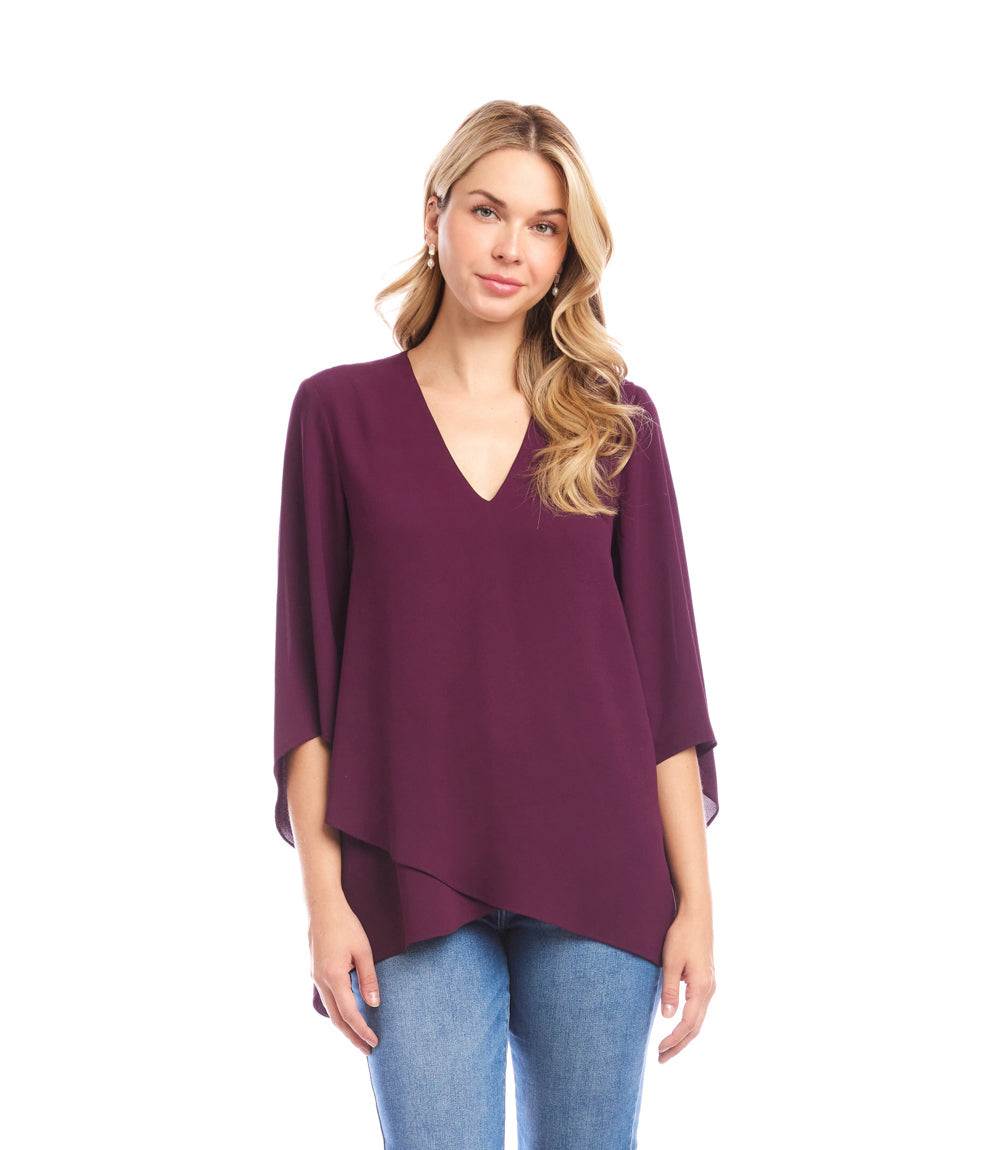 Woman wearing a purple Bracelet Sleeve Asymmetric Top with V-neck and layered asymmetrical hem paired with blue jeans.