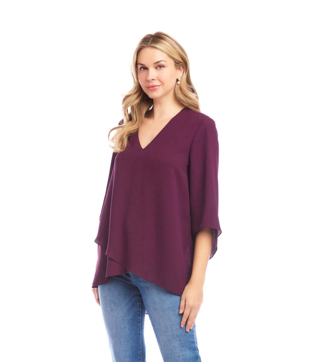 Woman wearing a purple Bracelet Sleeve Asymmetric Top with V-neck, flare sleeves, and layered asymmetrical hem paired with blue jeans.