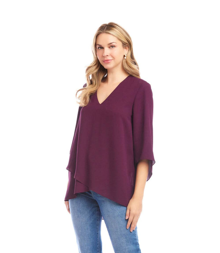 Woman wearing a purple Bracelet Sleeve Asymmetric Top with V-neck, flare sleeves, and layered asymmetrical hem paired with blue jeans.
