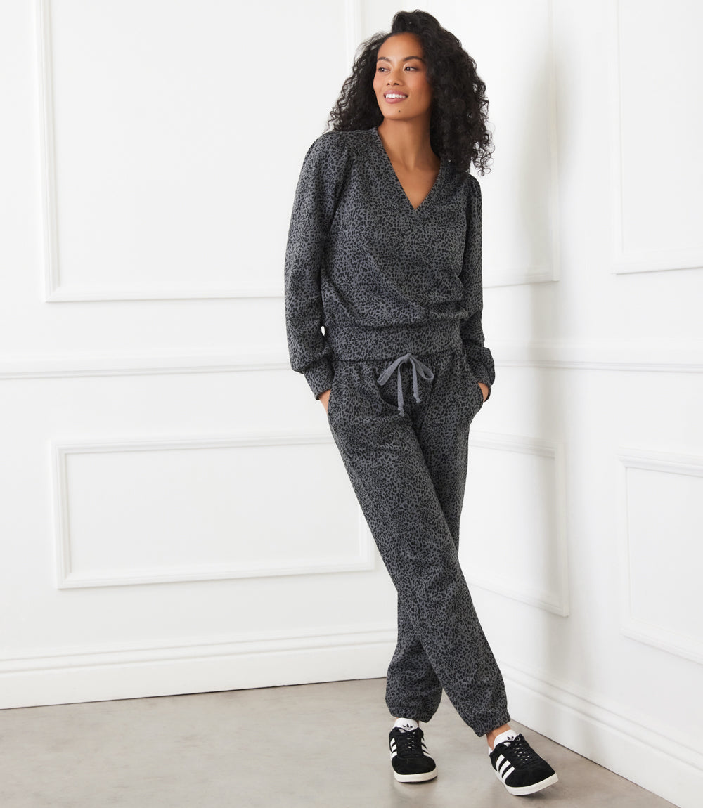 Woman wearing gray leopard print animal print sweatpants with drawstring waist and elasticized ankles, styled with matching top and black sneakers