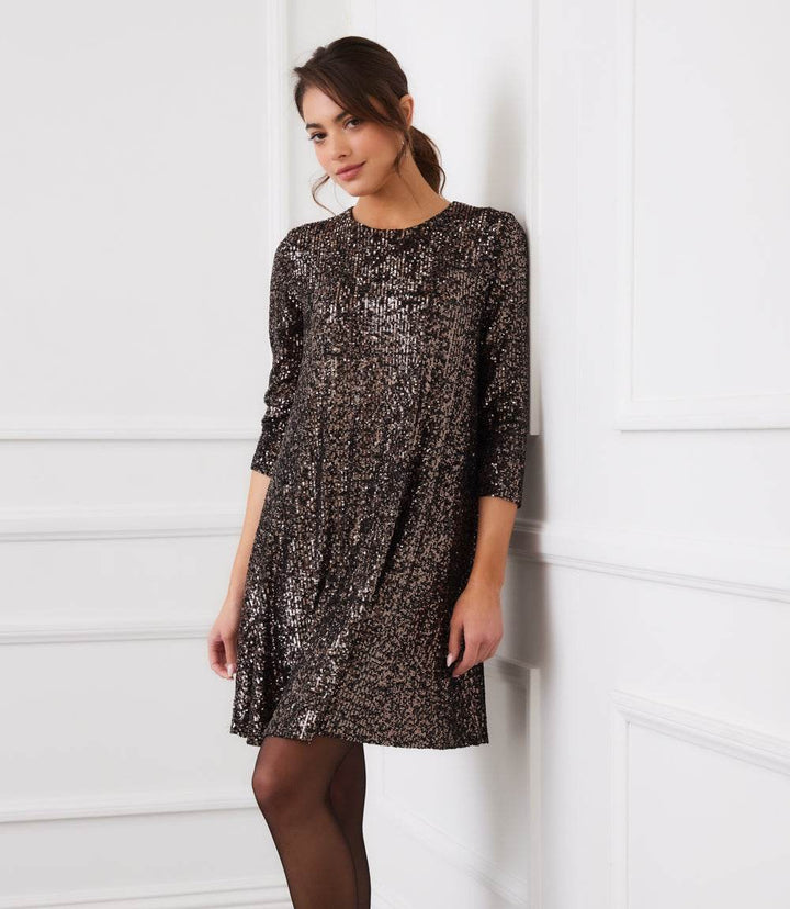Woman wearing a 3/4 sleeve sequin swing dress with scoop neckline and back keyhole closure, above knee length.