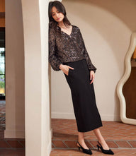 woman wearing black blouson sleeve sequin V-neck top and black skirt standing indoors