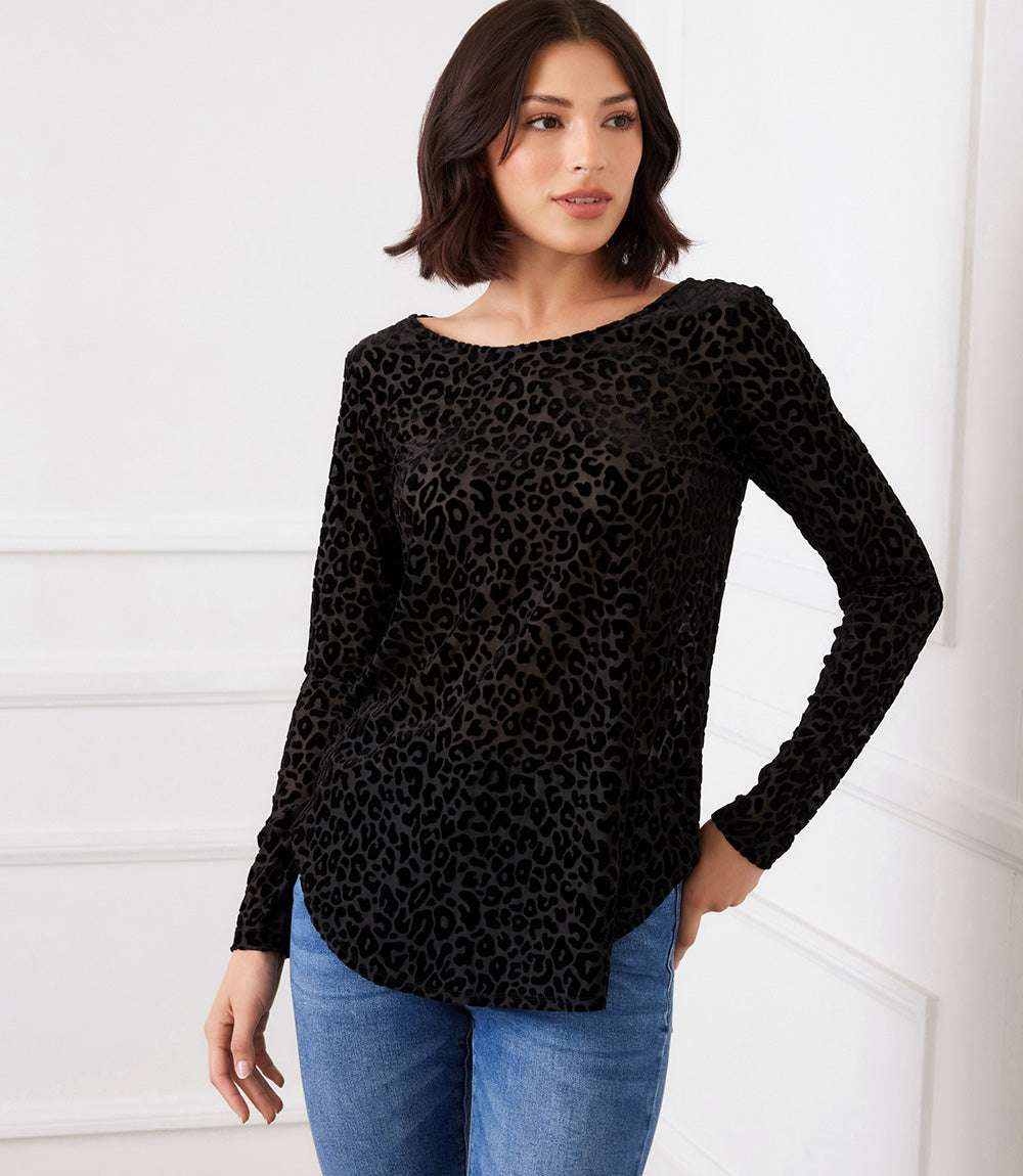 Woman wearing long sleeve velvet burnout shirttail top with black leopard pattern and scoop neckline paired with blue jeans