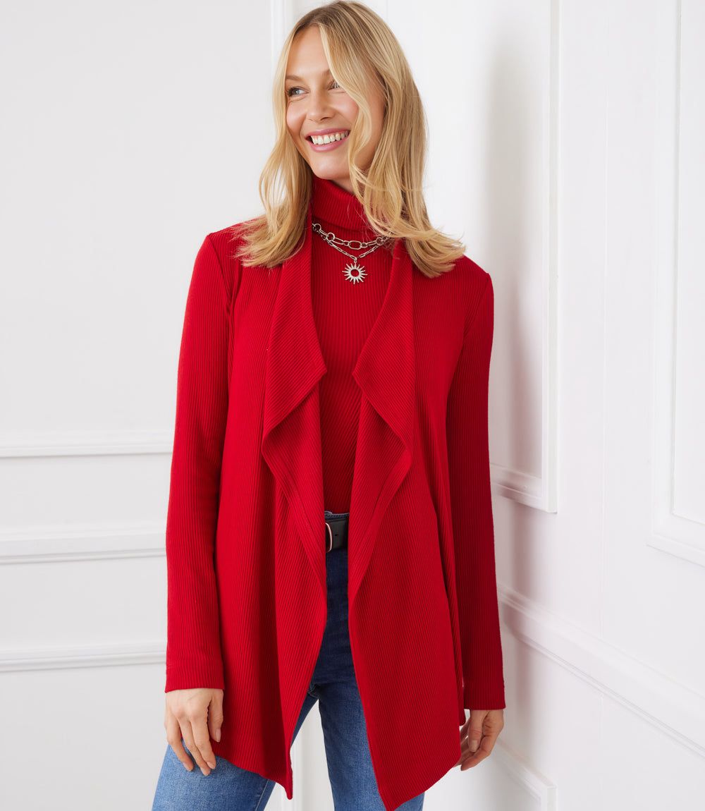 Woman wearing a red long sleeve ribbed drape front cardigan with open neckline and high-low hem
