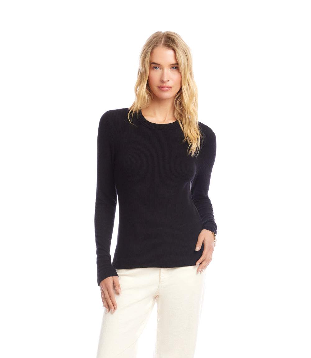 Woman wearing black long sleeve ribbed crewneck top with slim fit and white pants