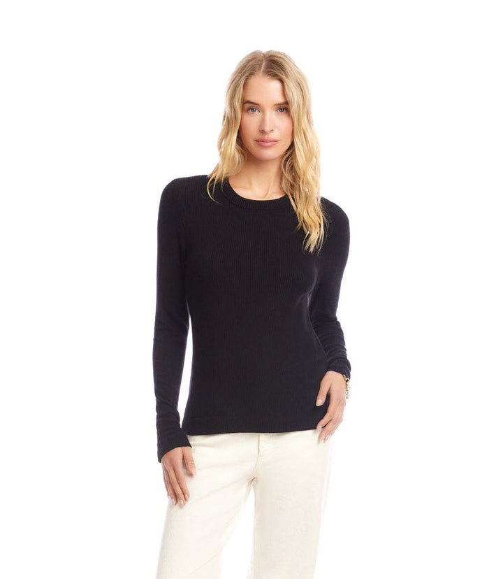 Woman wearing black long sleeve ribbed crewneck top with slim fit and white pants