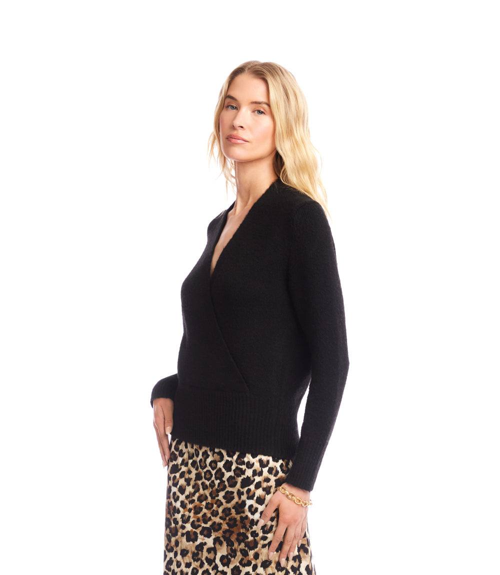 Woman wearing black faux wrap sweater with crossover V-neckline and drop shoulder sleeves paired with leopard print skirt