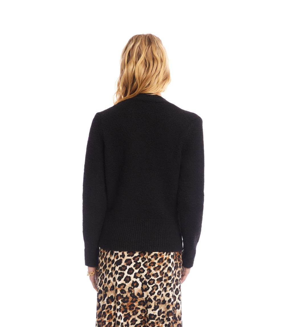 Back view of a woman wearing a black wrap sweater with long sleeves and drop shoulders paired with a leopard print skirt