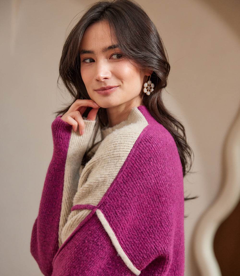Woman wearing a petite size colorblock mock neck sweater with purple and beige panels and an exposed seam detail.