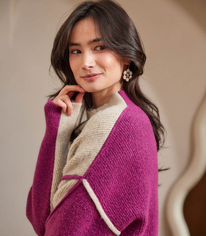 Woman wearing a petite size colorblock mock neck sweater with purple and beige panels and an exposed seam detail.