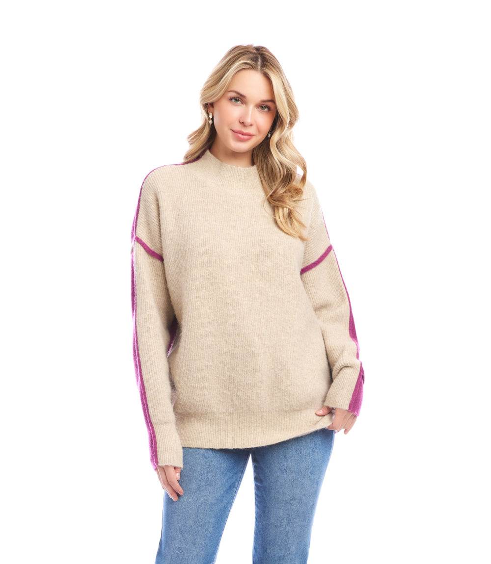Woman wearing beige colorblock mock neck sweater with purple stripes on sleeves and blue jeans