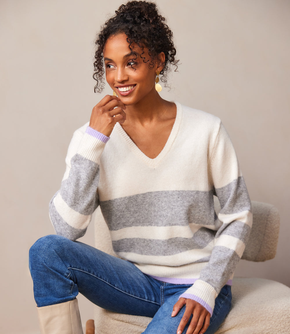 woman wearing off white and gray stripe V-neck sweater with relaxed fit and drop shoulder sleeves