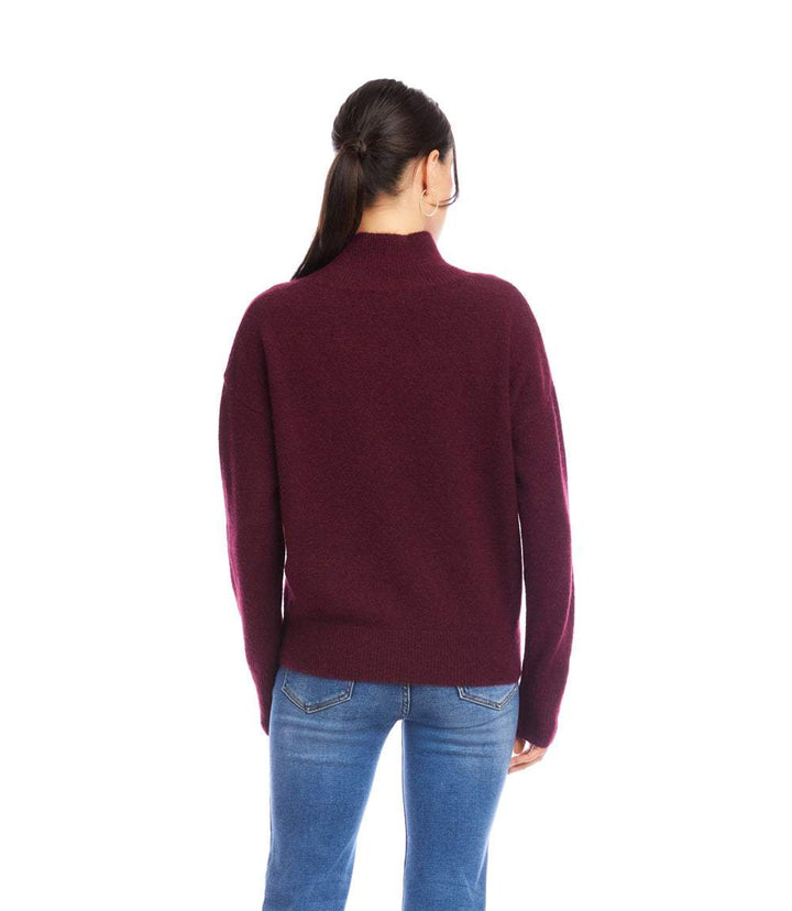 Back view of a petite size shawl collar sweater in burgundy worn by a woman with dark hair in a ponytail and blue jeans