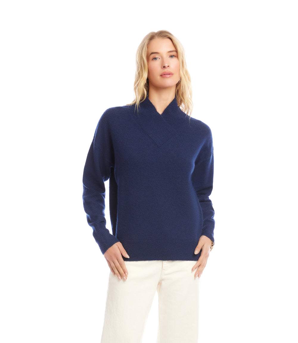 Woman wearing navy blue shawl collar sweater with long sleeves and drop shoulders paired with white pants