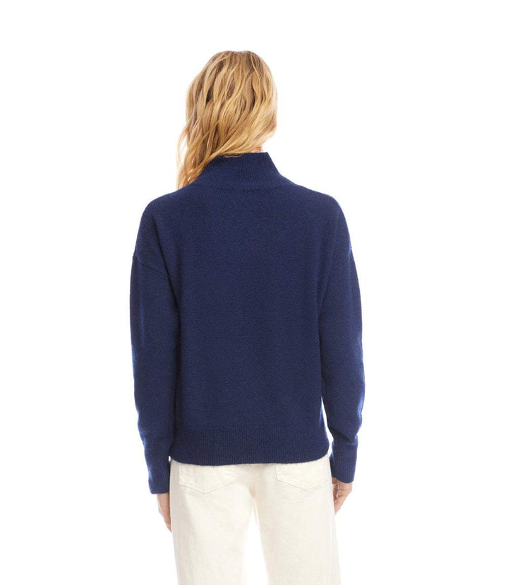 Back view of a navy blue shawl collar sweater with long sleeves and relaxed fit on a model wearing white pants