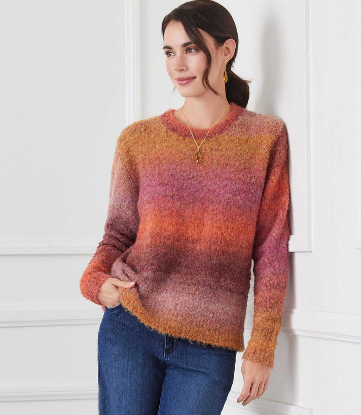 Woman wearing an ombre boucle sweater with a soft, loose fit and warm gradient colors paired with blue jeans.