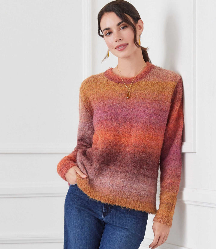 Woman wearing ombre boucle sweater in warm tones with loose fit and crew neck paired with blue jeans