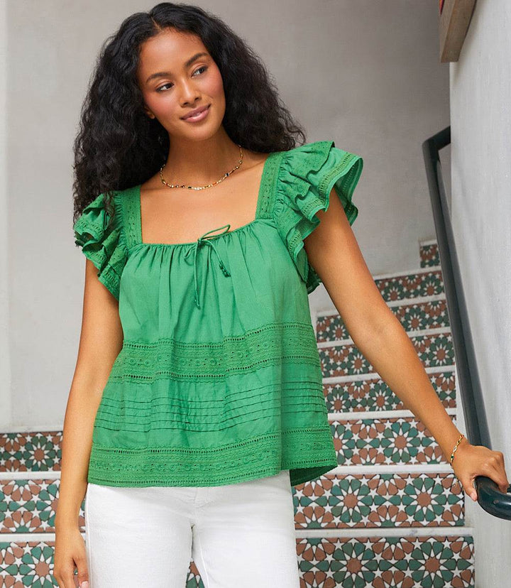 Green embroidered ruffle sleeve blouse with square neck worn with white pants