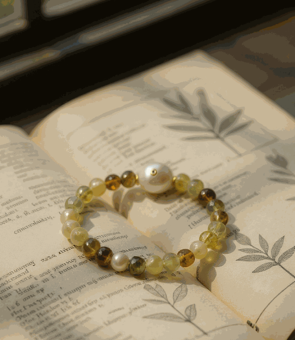Gemstone and pearl bracelet with multicolored green garnet and gold-plated brass beads on an open book background