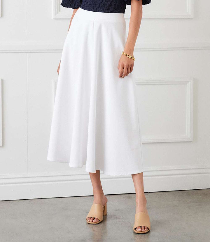White midi circle skirt with flowy silhouette and elasticized waistband modeled indoors