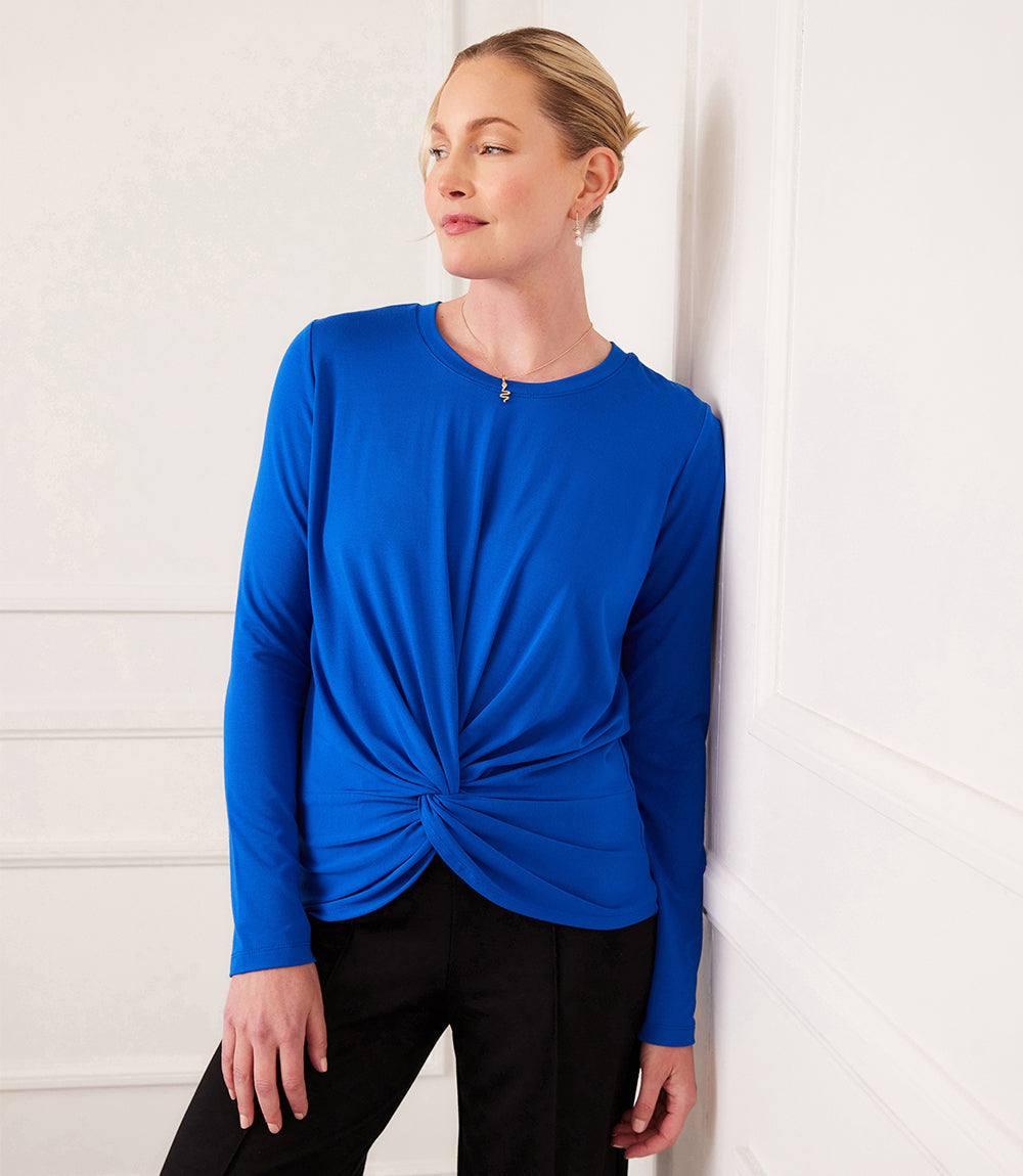 Woman wearing blue long-sleeve fitted twist front top with crew neck and twist hem