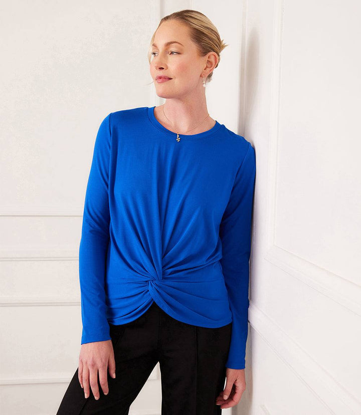 Woman wearing blue long-sleeve fitted twist front top with crew neck and twist hem