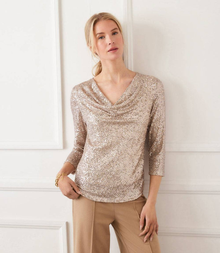 Woman wearing 3/4 sleeve drape front sequin mesh top with relaxed fit in light gold color