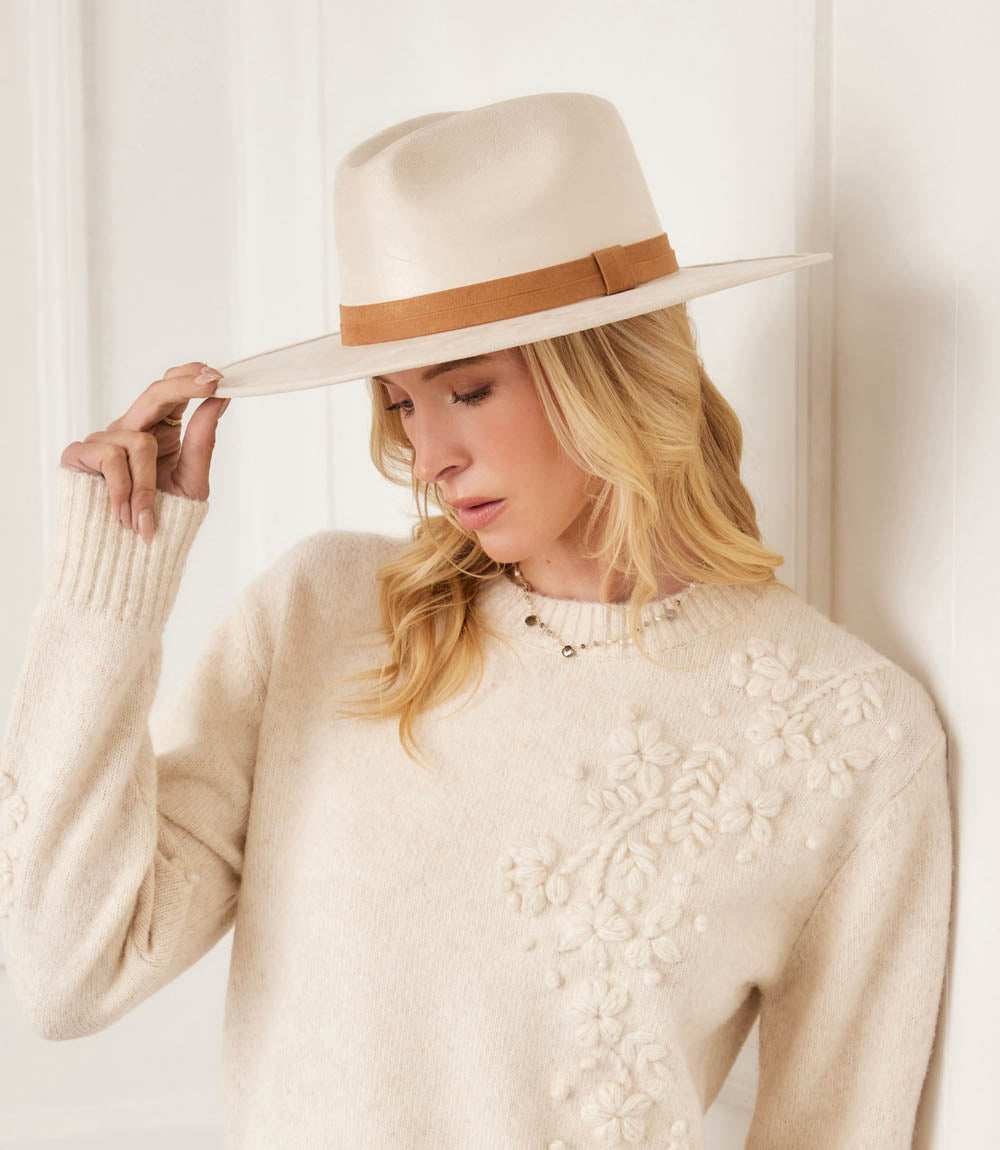 Woman wearing beige faux suede fedora hat with brown band and cream floral sweater