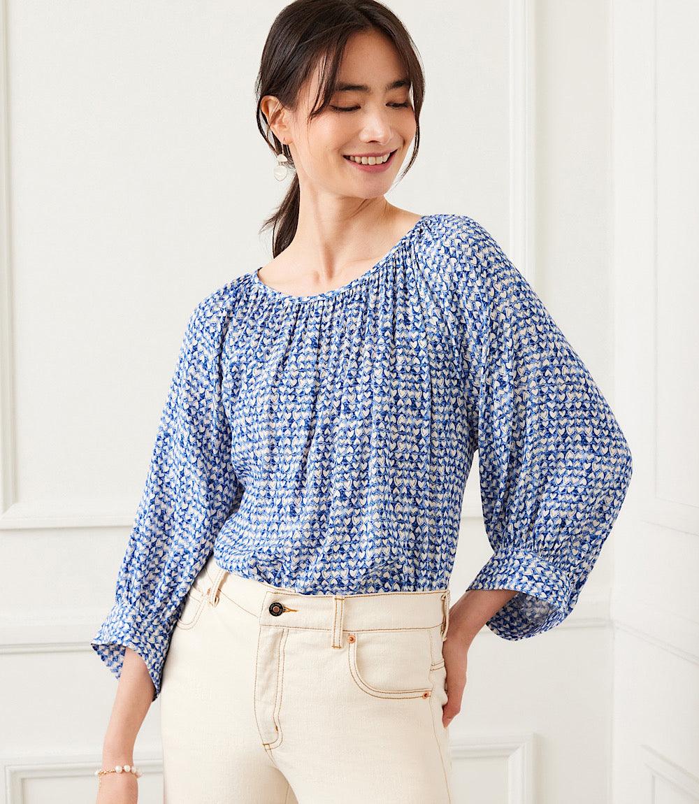 Woman wearing blue heart print blouson sleeve top with boat neck and relaxed fit paired with light pants