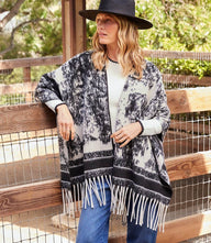 Brushed jacquard knit poncho with open front and fringe trim in bold abstract print
