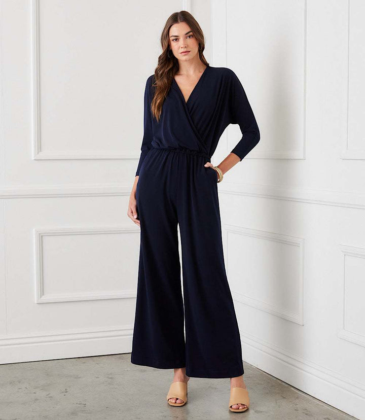 Woman wearing navy wide-leg travel jersey jumpsuit with crossover V-neck and elastic waistband