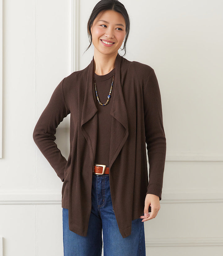 woman wearing brown long sleeve ribbed drape front cardigan with open neckline and blue jeans indoors