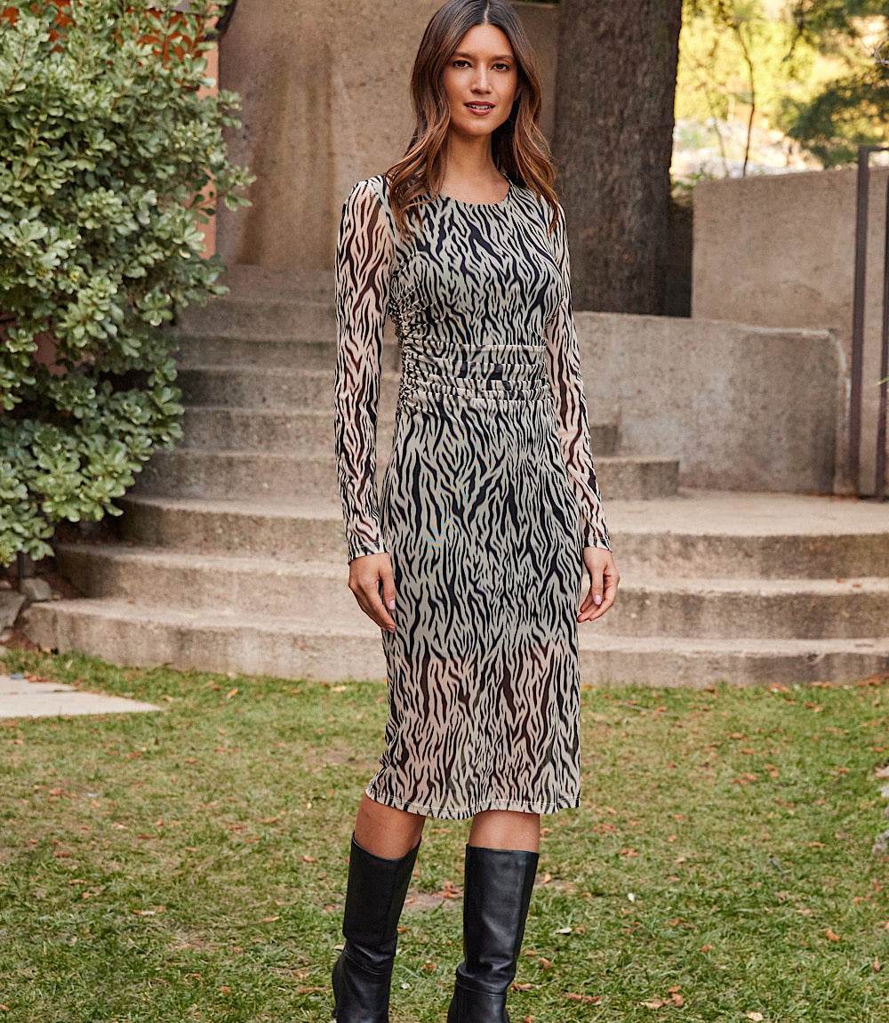 Woman wearing a zebra print side shirred midi mesh dress with long sleeves and scoop neck outdoors