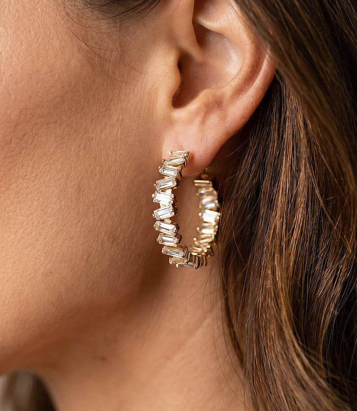 Angled crystal hoop earrings with clear blue crystals and 14k gold finish, 3-inch circumference