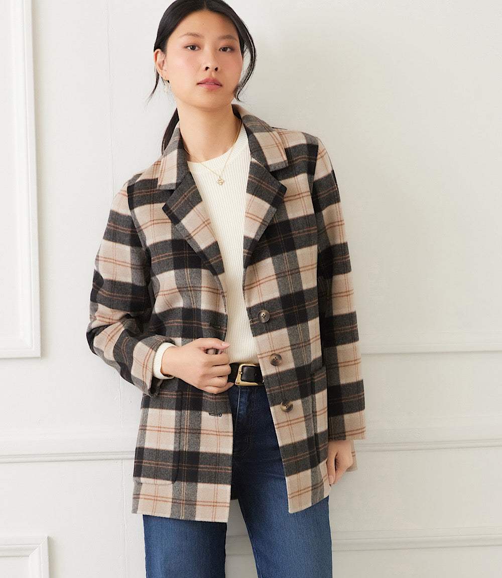Woman wearing oversized brushed plaid blazer in beige, black, and brown with notched collar and button closure
