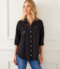 Woman wearing black long sleeve cutout embroidery shirt with button-up front and collar